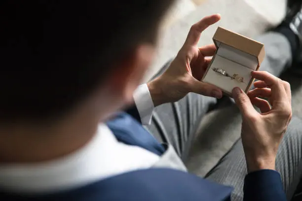 Man looking at wedding rings in a jewelry box in his hand