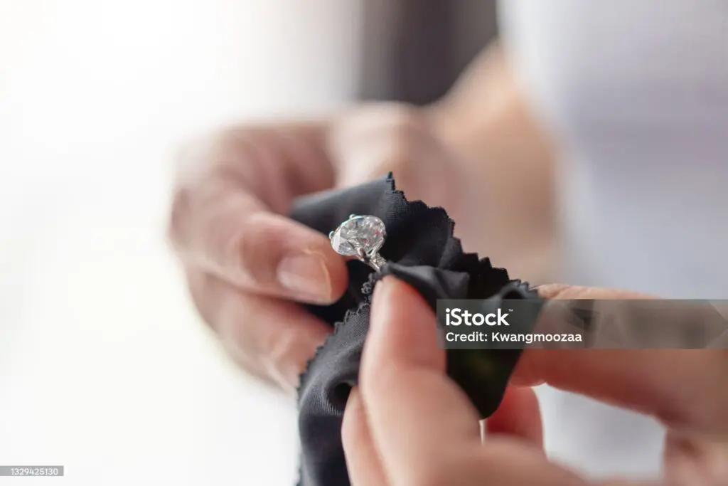 Jeweler cleaning jewelry diamond ring with fabric cloth